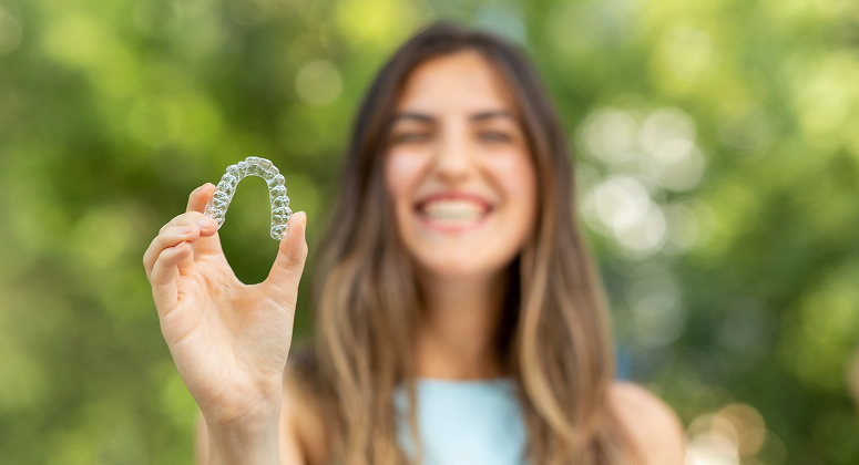 Patient holding a custom Invisalign clear aligner at Stewart Smiles, a trusted Franklin Invisalign provider